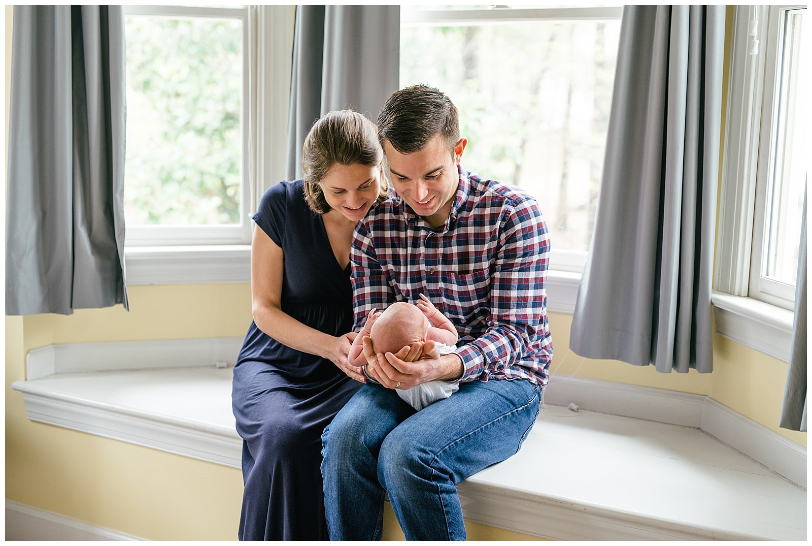 parents holding baby in bay window