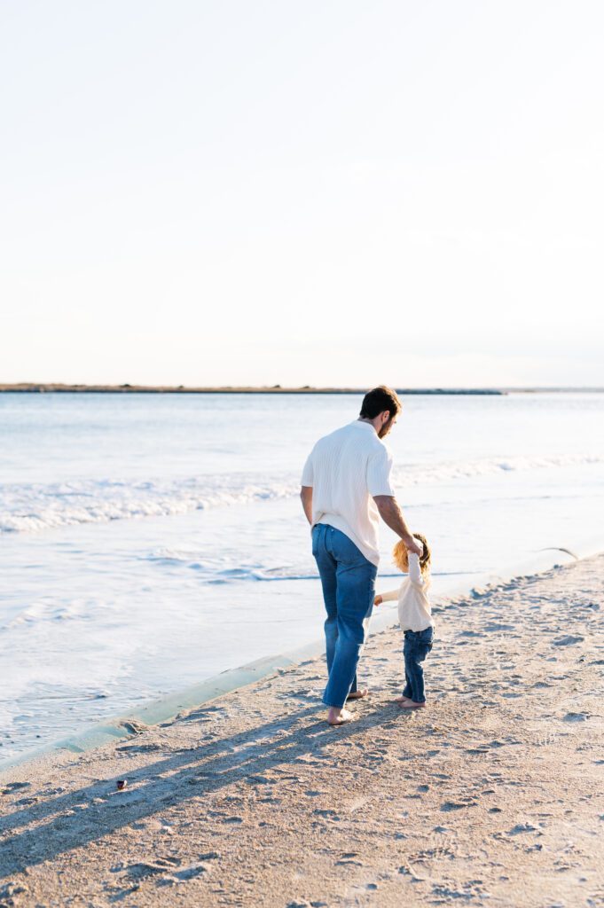 dad walking with toddler along the beach