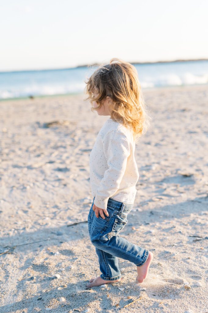 toddler boy with blonde hair walking along beach